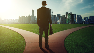 You’ve Been Suspended – Were You Ready? Businessman standing in front of fork with downtown in distance