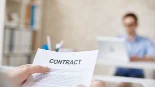 Contract Construction Smarts: Helpful Provisions for Dispute Resolution Businessmember holding contract with person in background