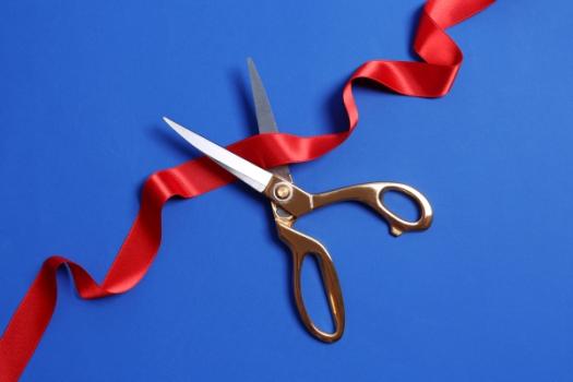 Scissors cutting through curly red tape