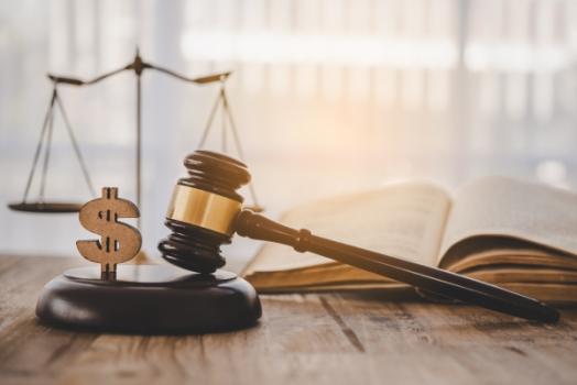 Gavel, scale, and lawbook on desk with dollar sign