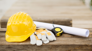 Drastic Rebuild Resurrects Graves' Landmark Portland Building Hardhat gloves measuring tape and plans resting on wooden table