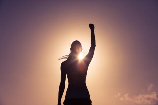 Woman in shadow with arm raised in triumph