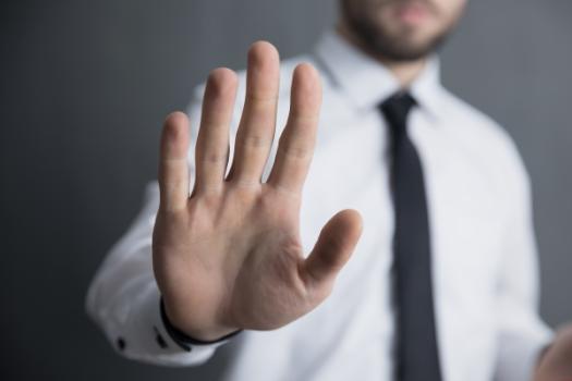 Man with hand raised in Don't or Stop gesture