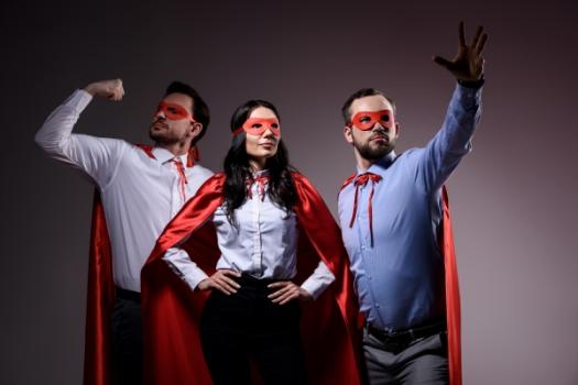 Two men and one woman wearing superhero capes