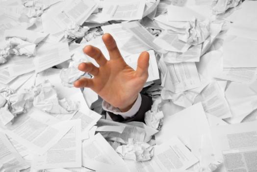 Hand reaching out of pile of paperwork