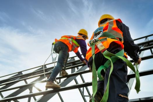 Two construction workers wearing safety harnesses