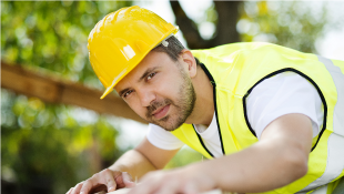 Construction worker smirking while working with wooden beam