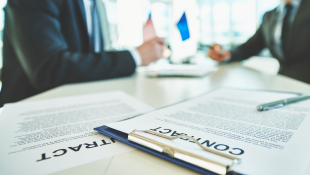 Prefabrication Contract Considerations Two businessmen across from table with contracts