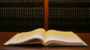 Law book open on desk in front of bookshelf