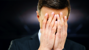 Businessman with hands covering face