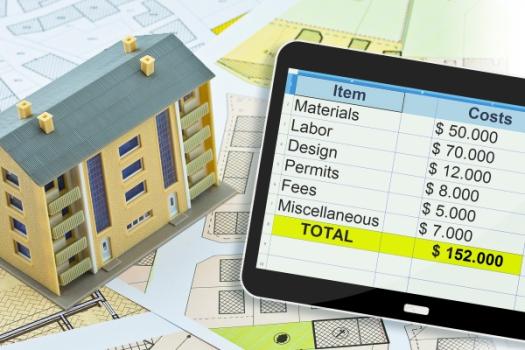 House next to tablet displaying spreadsheet