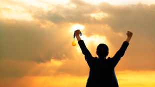 Businessman holding up both hands in victory gesture sunset background