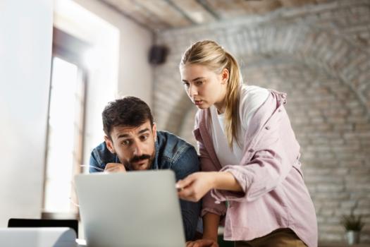 Person pointing to something on computer to other person