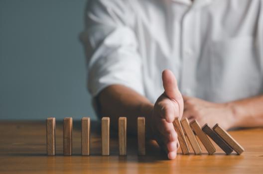 2026 Top Business Risks for Construction and Engineering Companies Hand stopping falling dominoes
