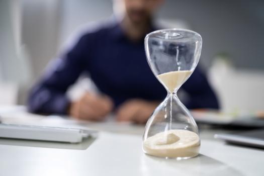 The Deadline to File Suit on a Public Works Payment Payment Bond is Triggered by a Claimant’s Work on a Project Not by a Claimant’s Work Under a Contract Hourglass on desk