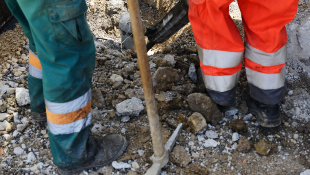 Construction workers outside with pick in ground