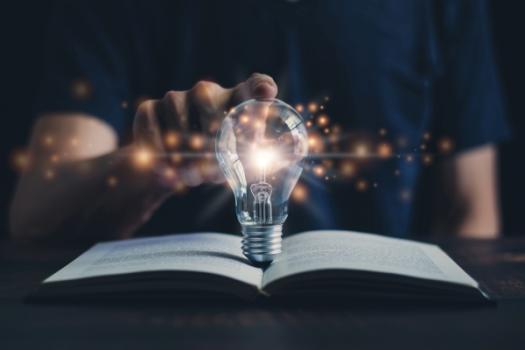 Lit lightbulb on open book