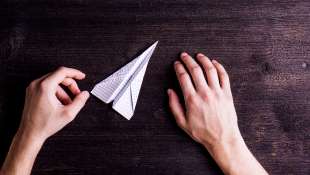 Desk hands holding paper airplane