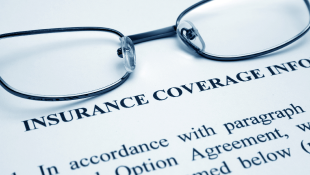 Glasses lying on Insurance Coverage document