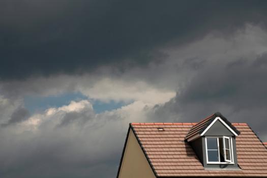 Intensifying Wildfires and Hurricanes Raise New Questions About How America Builds Homes Top of home with storm clouds in sky
